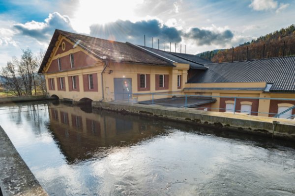 Altes Kraftwerk in der Steiermark mit Spiegelung im Wasser unter blauem Himmel
