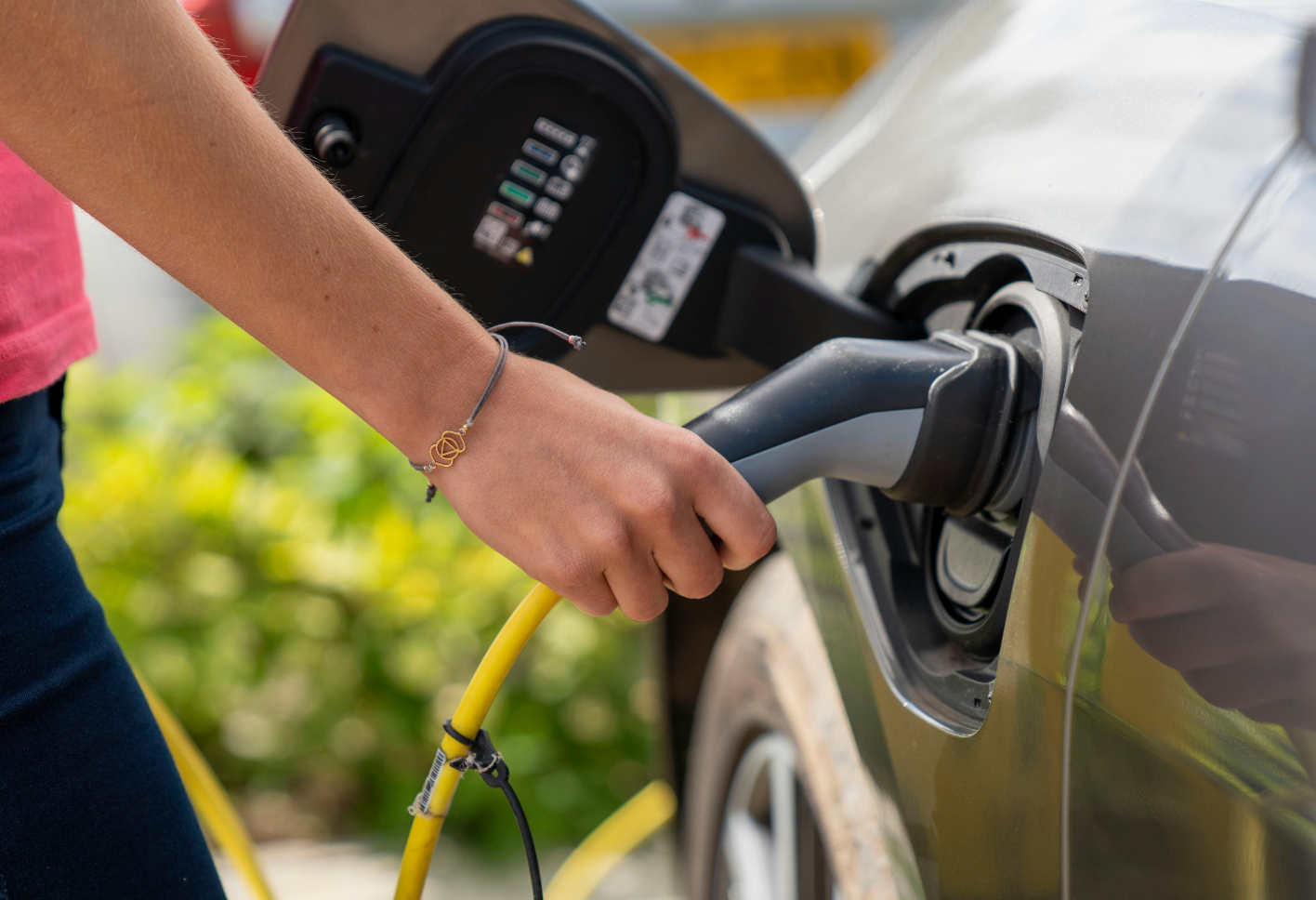 Ein weibliche Hand steckt ein E-Auto-Kabel ein