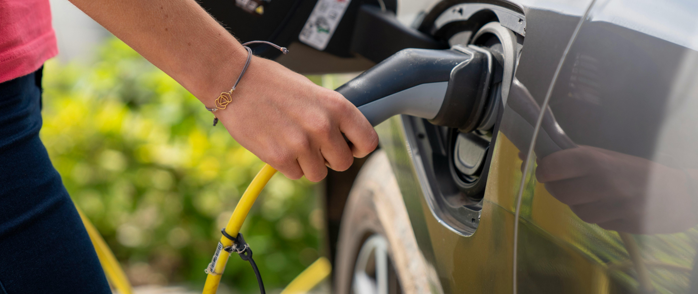 Eine weibliche Hand steckt ein E-Auto-Kabel ein