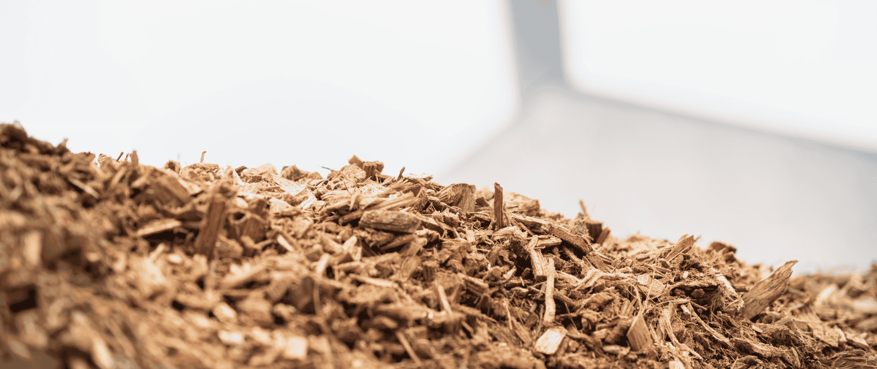 Ein Haufen Hackschnitzel vor einem Biomasseheizkraftwerk