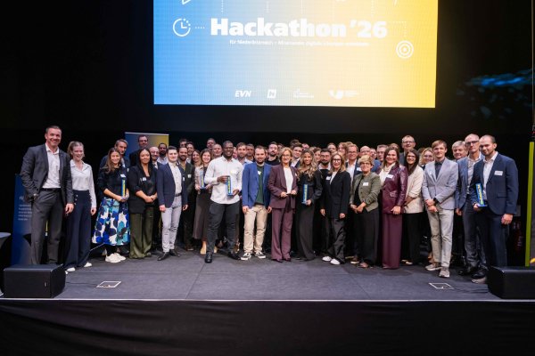 Hackathon '26 Gewinnerteam mit Pokalen vor LED-Leinwand in St. Pölten