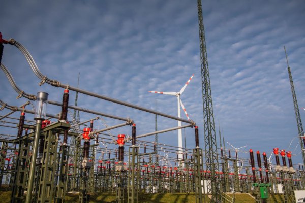 Umspannwerk mit Windrädern unter blauem Himmel mit Wolken